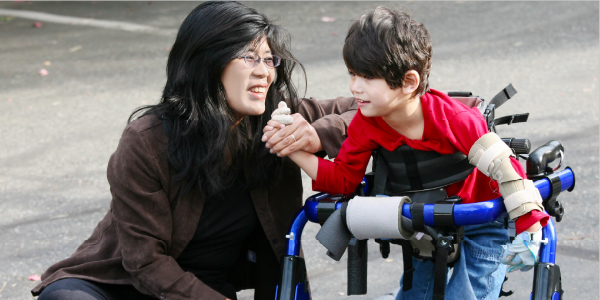 Teacher with an elementary school student standing in an specialized walker